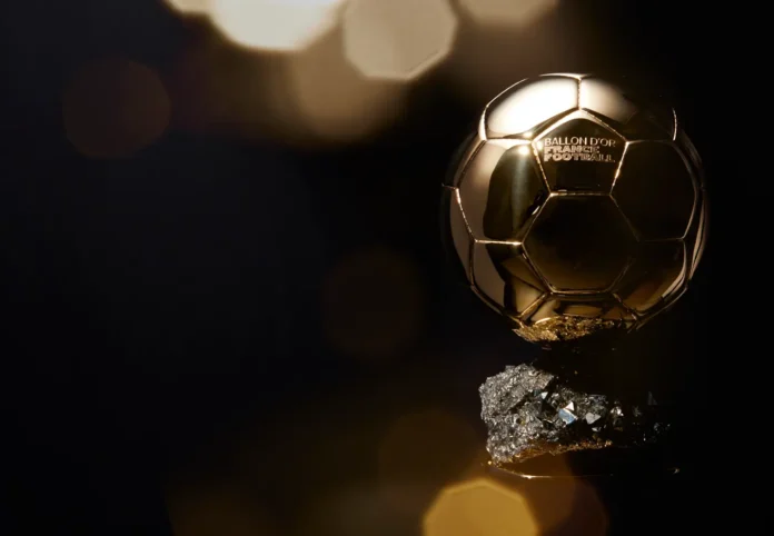 Trofi Ballon d'Or berbentuk bola emas di atas dudukan berkilau dengan latar belakang gelap